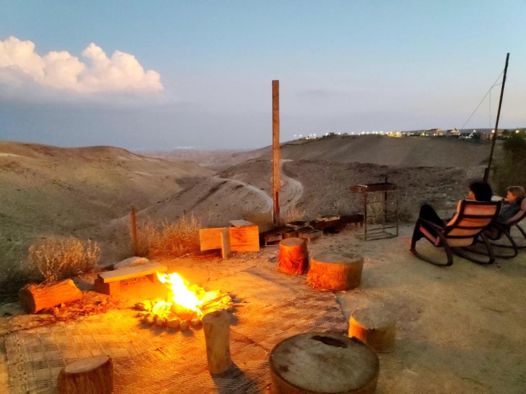 阿拉德Desert's Edge Eco Tent的坐在火旁椅子上的人