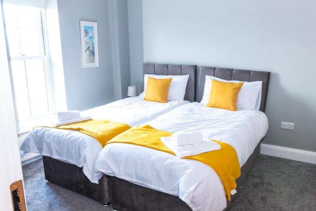 伦敦德里Castle gate lodge的一张大床,配有黄色和白色的床单和枕头