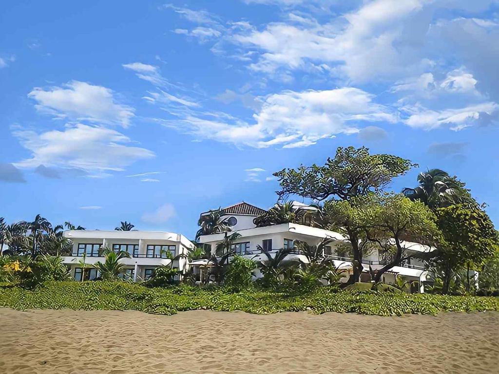 佩达西镇OP Apartahotel Pedasí Ocean Properties的海滩前有树木的大型白色建筑