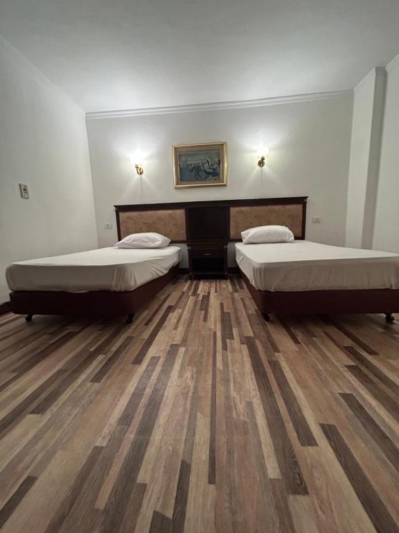 开罗The New Garden Palace Hotel的铺有木地板的客房内的两张床