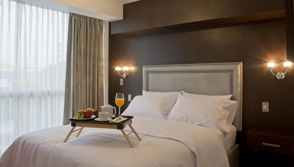 特鲁希略阿沃精品酒店的酒店客房,配有一张带水果和葡萄酒托盘的床。