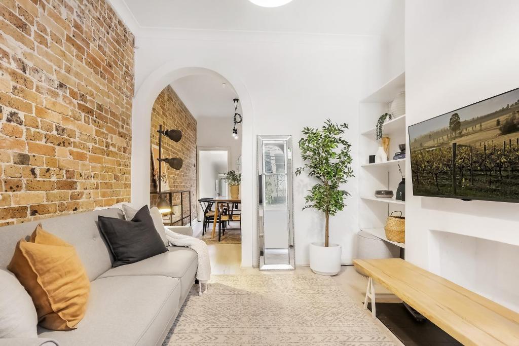悉尼Surry Hills l 2 Bedroom Terrace Home的客厅配有白色沙发和砖墙