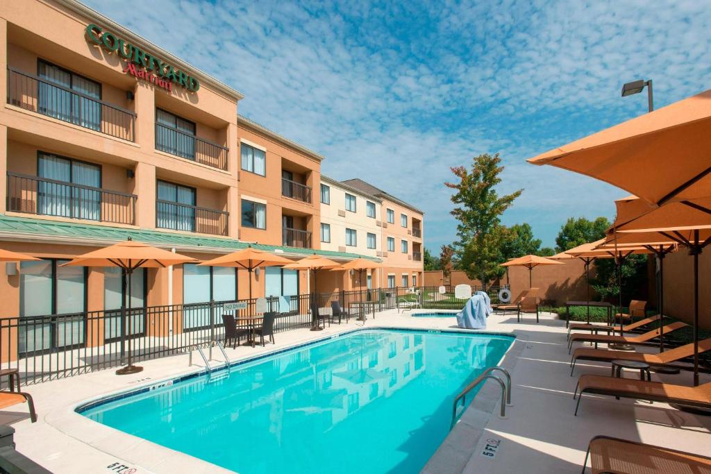 普拉特维尔Courtyard by Marriott Montgomery Prattville的游泳池位于酒店,配有桌椅和遮阳伞