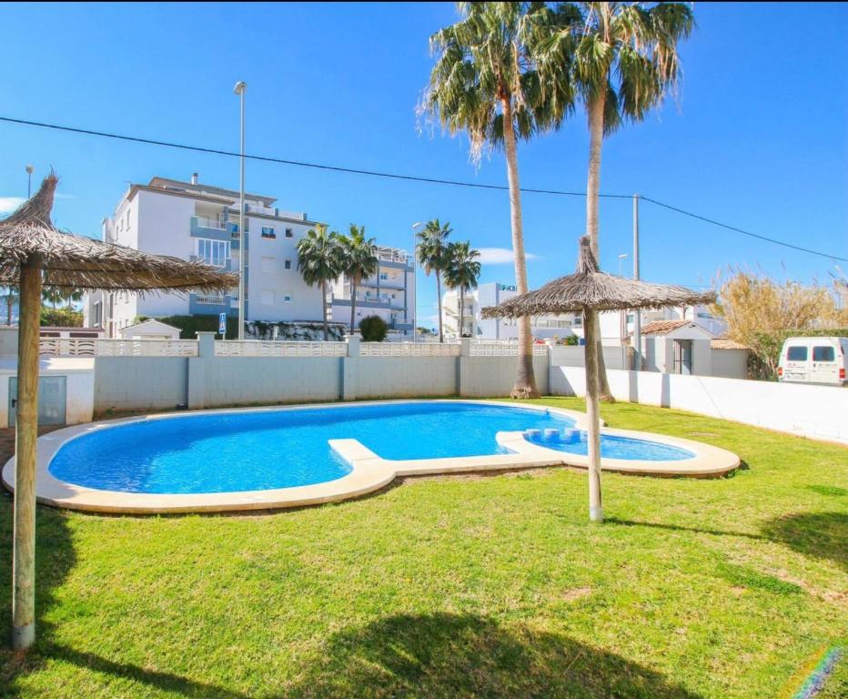 德尼亚Apartamento con terraza y acceso directo a piscina的一个带两把遮阳伞的庭院内的游泳池
