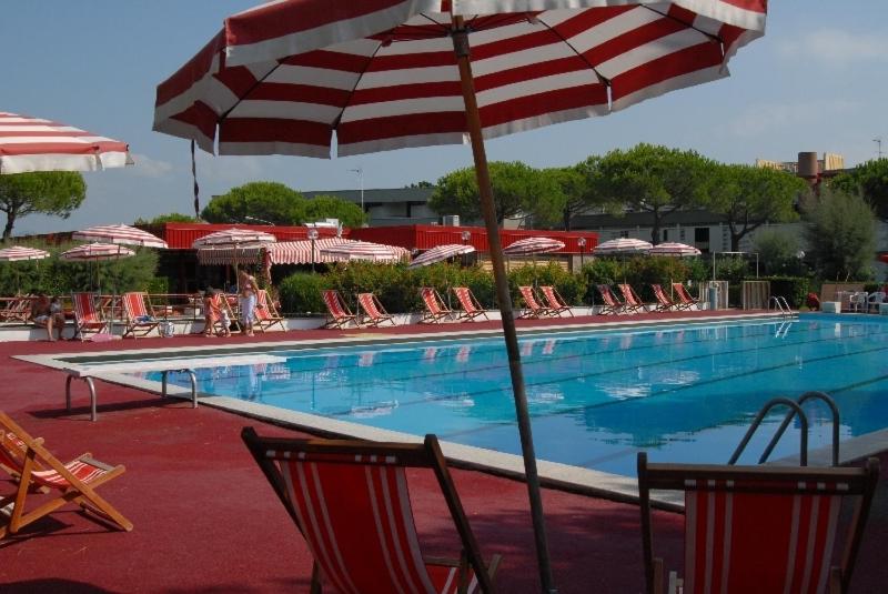 毕博纳的码头Apartments Via Dei Platani的一个带椅子和遮阳伞的游泳池以及一座池畔修道院