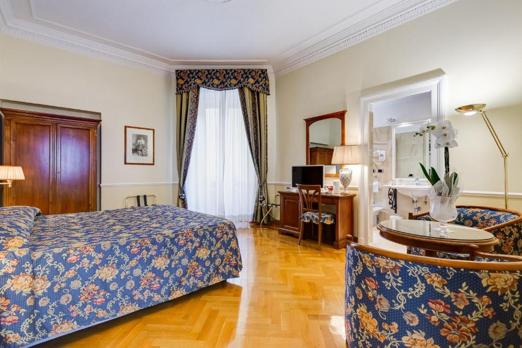 罗马Hotel Cellini的一间卧室配有一张床、一张书桌和一面镜子