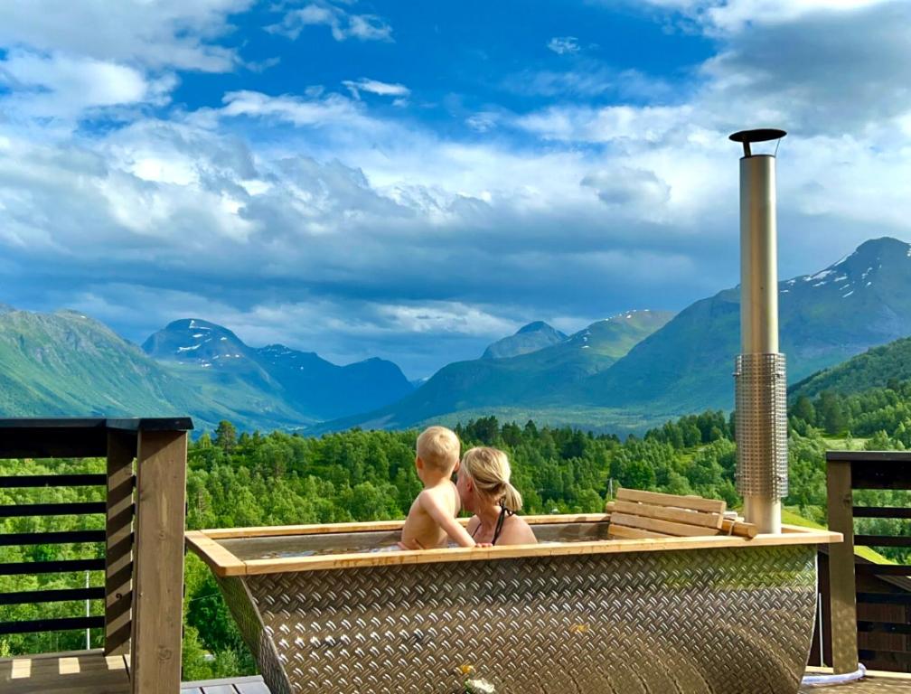 斯特兰达Unique Romantic Cabin with Mountain View at Strandafjellet, Mivo X的身后山 ⁇ 热水浴池中的男孩和女孩