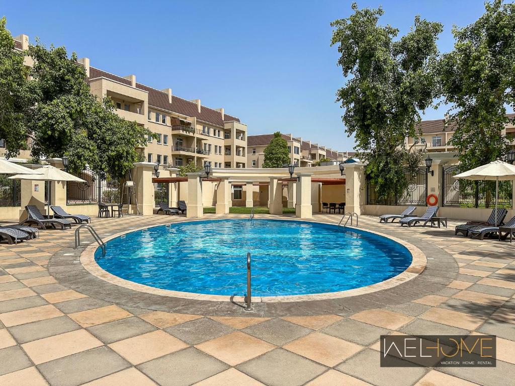 迪拜WelHome - Elegant Apartment Retreat at Widcombe House 3的庭院内的游泳池,带椅子,大楼
