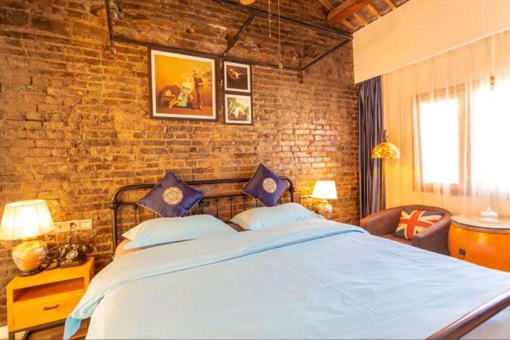 昆明龚禧里•初见酒店的一间卧室设有一张大床和砖墙