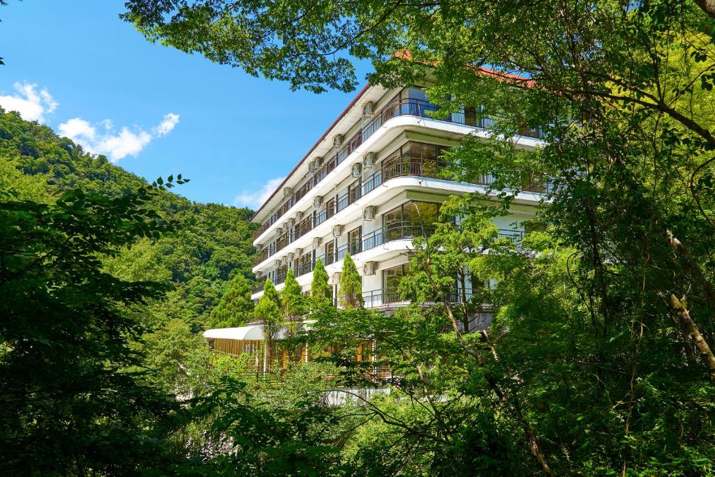 箱根箱根湯本ホテル的山丘上高大的白色建筑,有树木