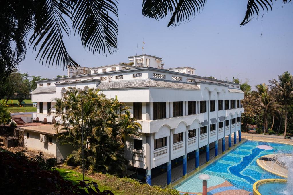 卡尔贾特U Rivergate Karjat的一座白色的大建筑,拥有游泳池和棕榈树