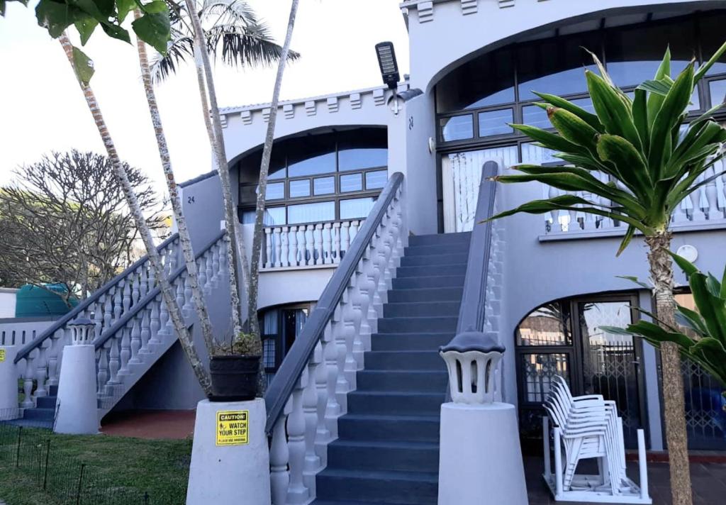 马盖特Uvongo cabanas的白色的建筑,有楼梯和棕榈树