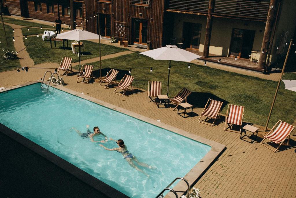 YasnogorodkaEden Resort的两人在带椅子和遮阳伞的游泳池游泳