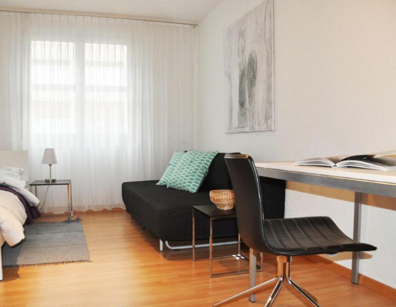 楚格Nest - Poststrasse 24的客厅配有书桌和沙发。