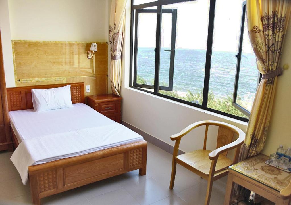 洞海Thăng Long Hotel的卧室配有床、椅子和窗户。