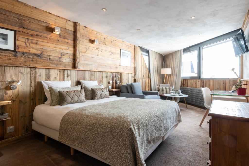 葱仁谷Hotel 3 Vallées Val Thorens的一间卧室设有一张大床和木墙