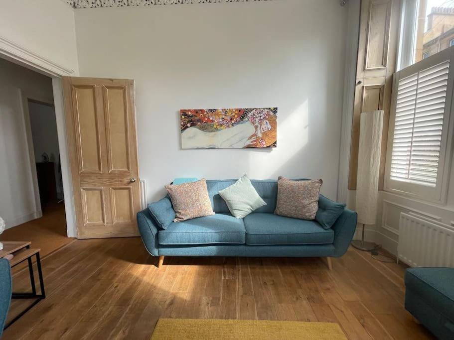 格拉斯哥Stunning West End Flat!的客厅配有蓝色沙发和绘画作品