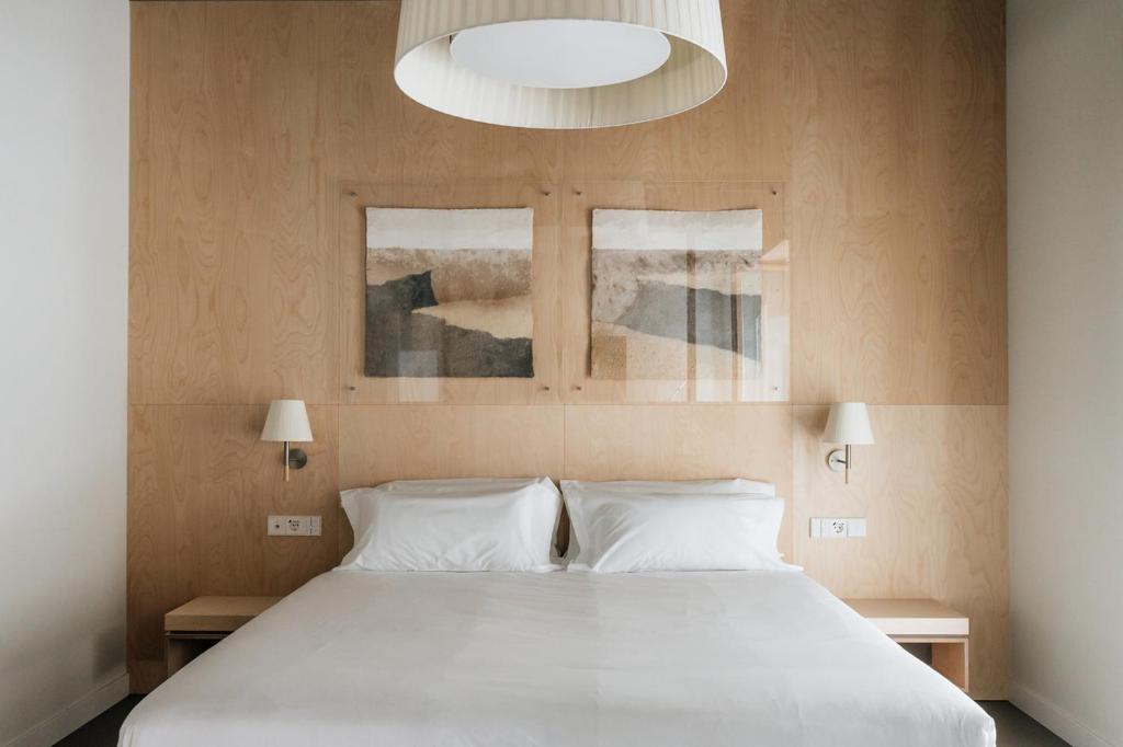 图德拉Hotel Santa Ana Tudela的卧室配有一张白色大床和两个窗户