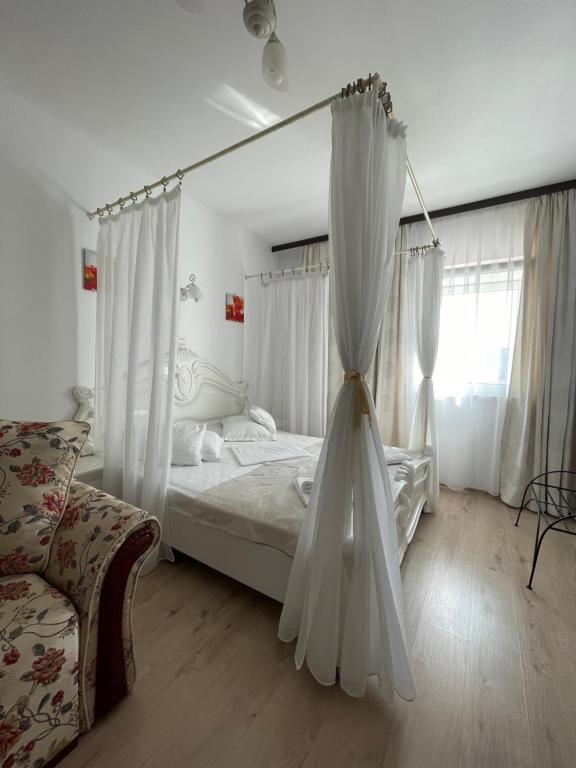 阿尔巴尤利亚Hotel Prestige的一间卧室配有带白色窗帘的床和沙发