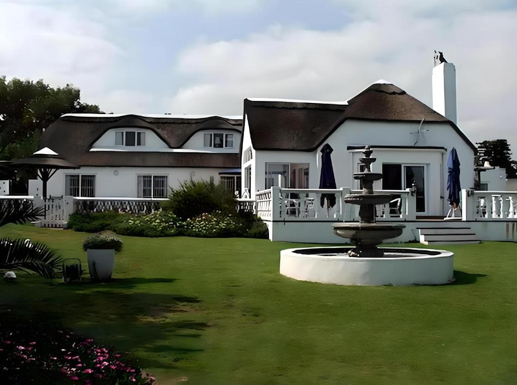 开普敦Lagoon Lodge的一座大白色房子,在院子里设有一个喷泉