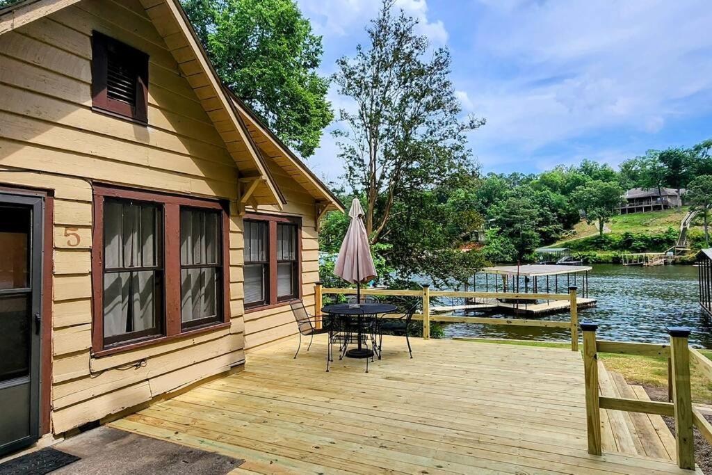 温泉城#05 - Lakefront Two Bedroom Cottage- Pet Friendly的木甲板配有桌子和遮阳伞
