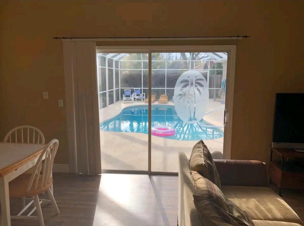 棕榈海岸Guest house withl kitchen living room 65" tv solar heated pool的客厅设有滑动玻璃门,可通往游泳池