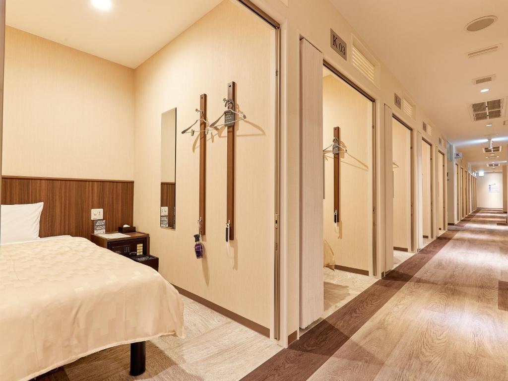 那霸Grand Cabin Hotel Naha Oroku for Men / Vacation STAY 62323的走廊,带一张床的酒店客房