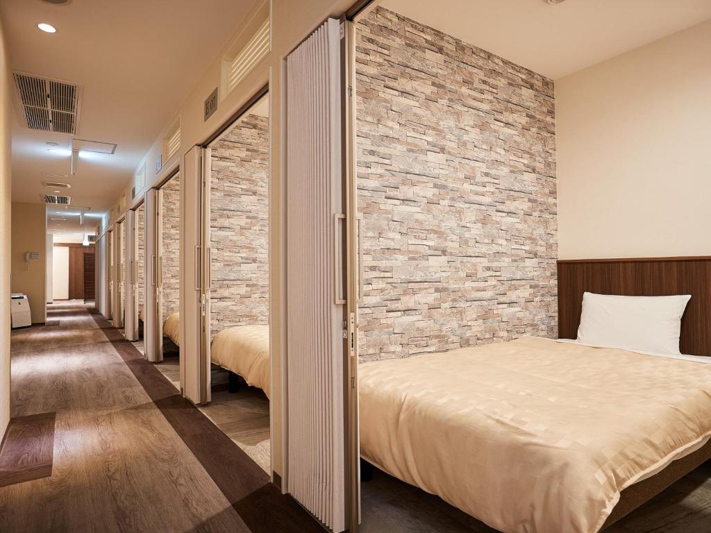 那霸Grand Cabin Hotel Naha Oroku for Women / Vacation STAY 62324的一间设有两张床和砖墙的房间
