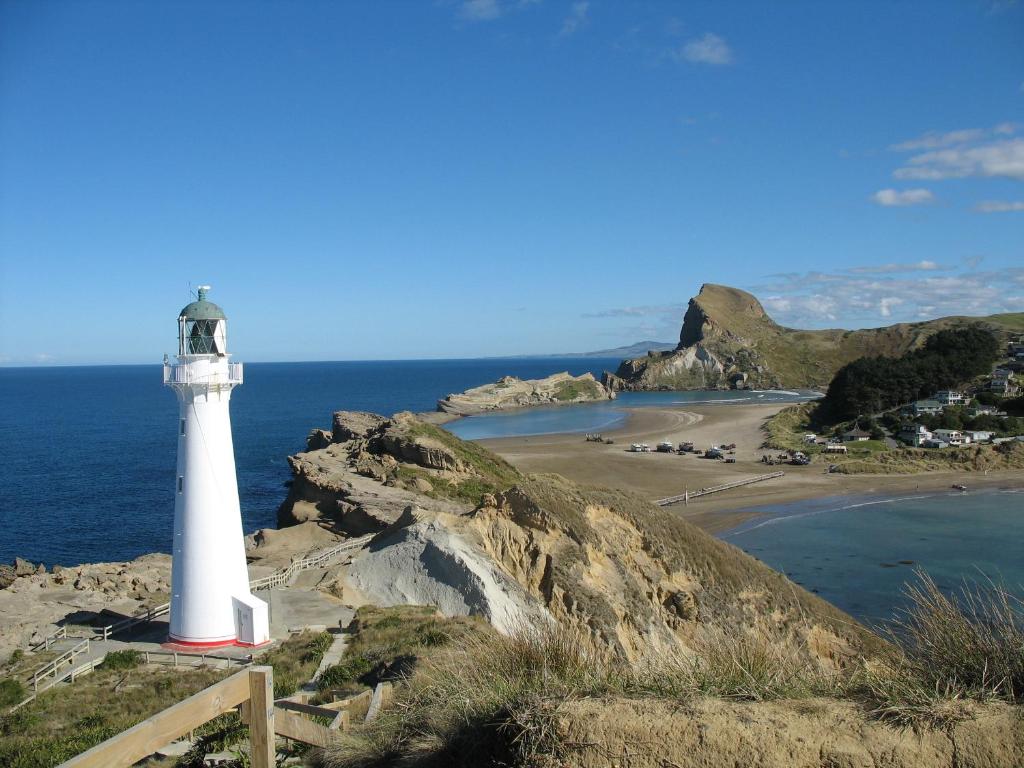 卡斯尔波因特Castlepoint Holiday Park & Motels的海滩边悬崖上的灯塔