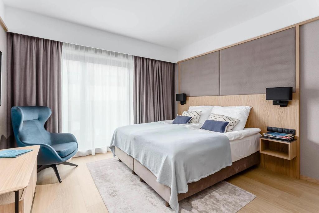 格但斯克Deo Plaza Old Town Gdańsk - Praia Apartaments的一间卧室配有一张大床和一张蓝色椅子