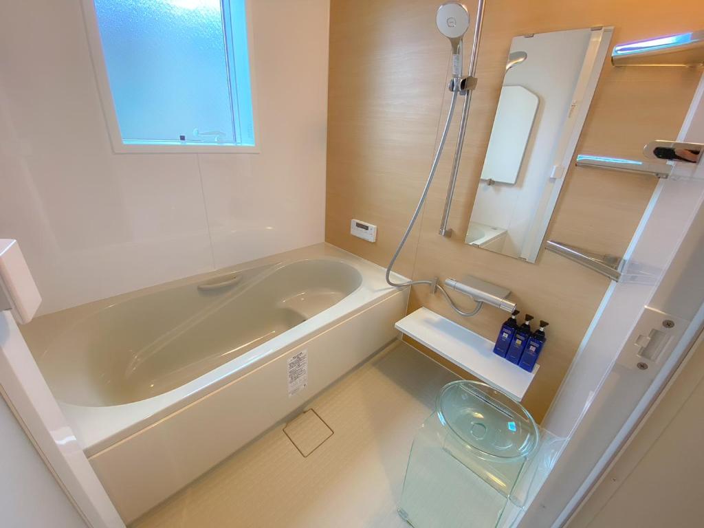 桑名市machiyado kuwanajuku edomachi25的带浴缸、水槽和镜子的浴室