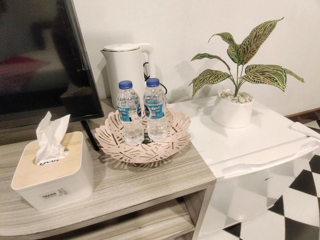 曼谷OYO 75446 Travis Inthamara 49的一张桌子,上面放着两瓶水和一株植物