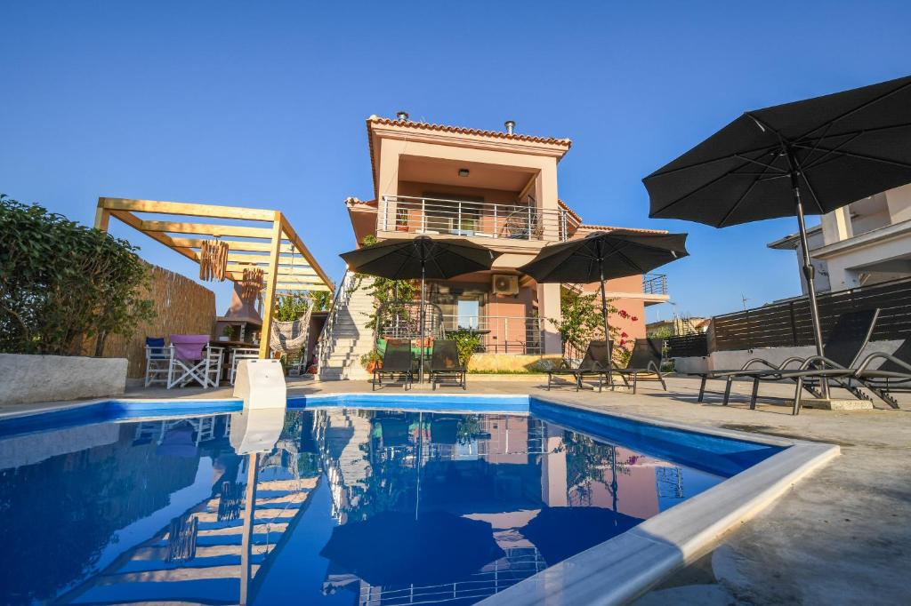 AmbelókipoiNektarios & Eftychia Suites的一座房子,设有一座带遮阳伞的游泳池
