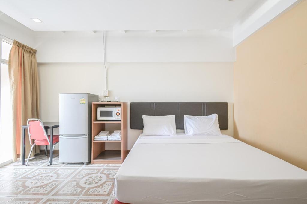 曼谷AC Habitat Bangkok的一间卧室配有一张床铺、一张桌子和一台冰箱