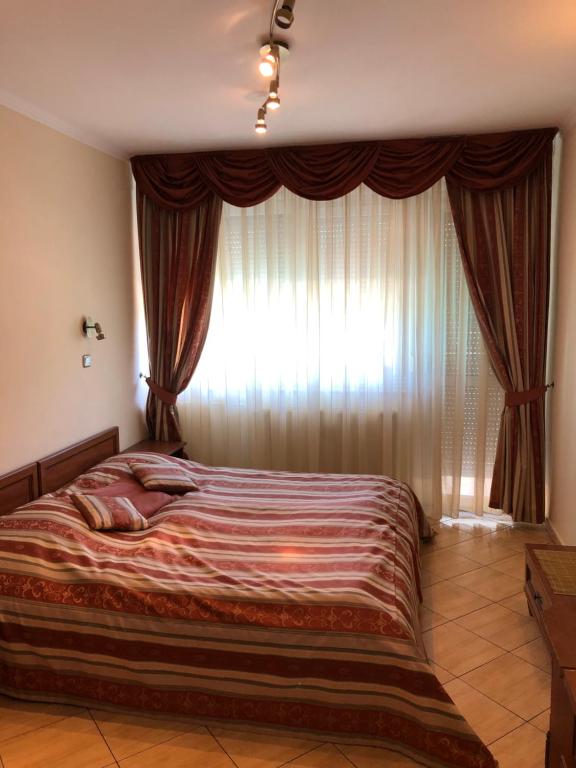 AjkaHotel Ajka 1的卧室内的一张床铺,设有大窗户
