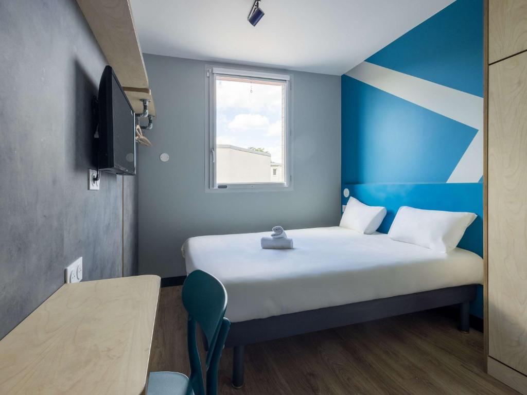 楠泰尔ibis budget Nanterre la Defense的一间卧室配有一张蓝色和白色条纹的床