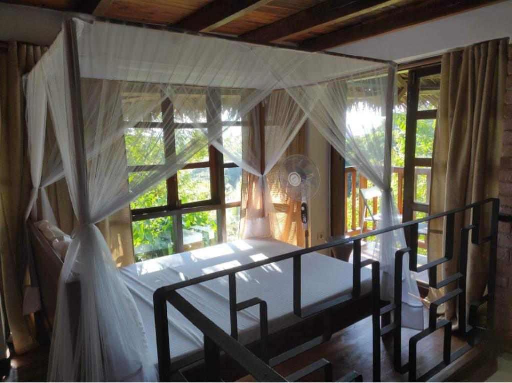 阿姆巴托洛阿卡Moemoea Lodge的一间卧室设有天蓬床和窗户。