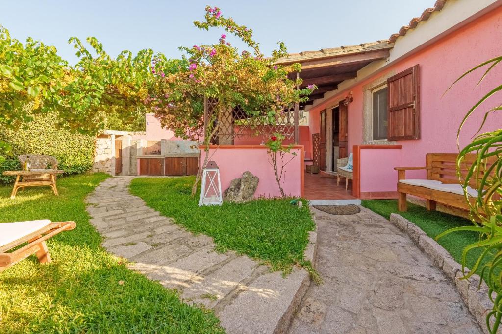 阿列恩图Casa Baia Vignola的一个带长凳和粉红色房子的花园