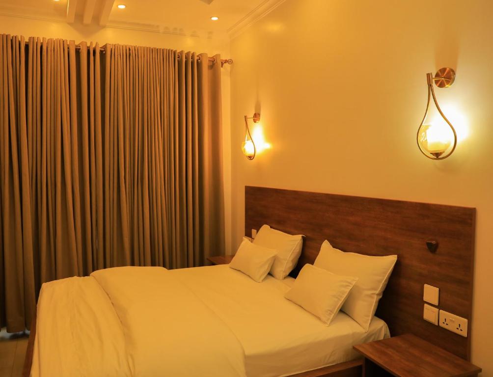 基加利ALLY NGALI MOTEL的卧室配有一张带白色床单和枕头的大床。