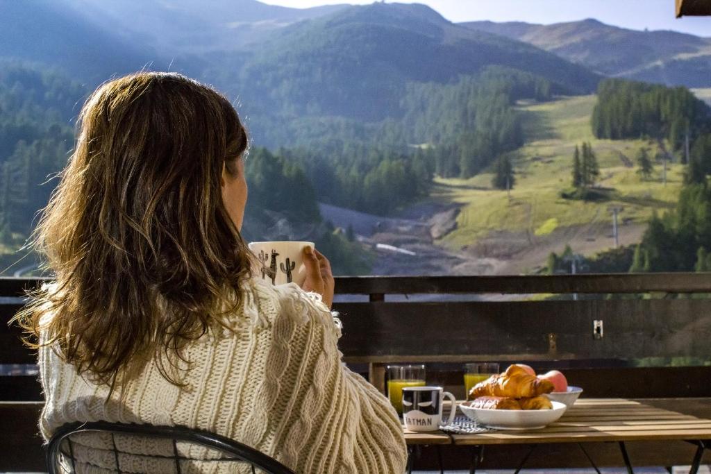 莱索尔Studio Cocon aux Orres 1650 au pied des pistes et vue montagne的坐在餐桌旁吃一碗食物的女人