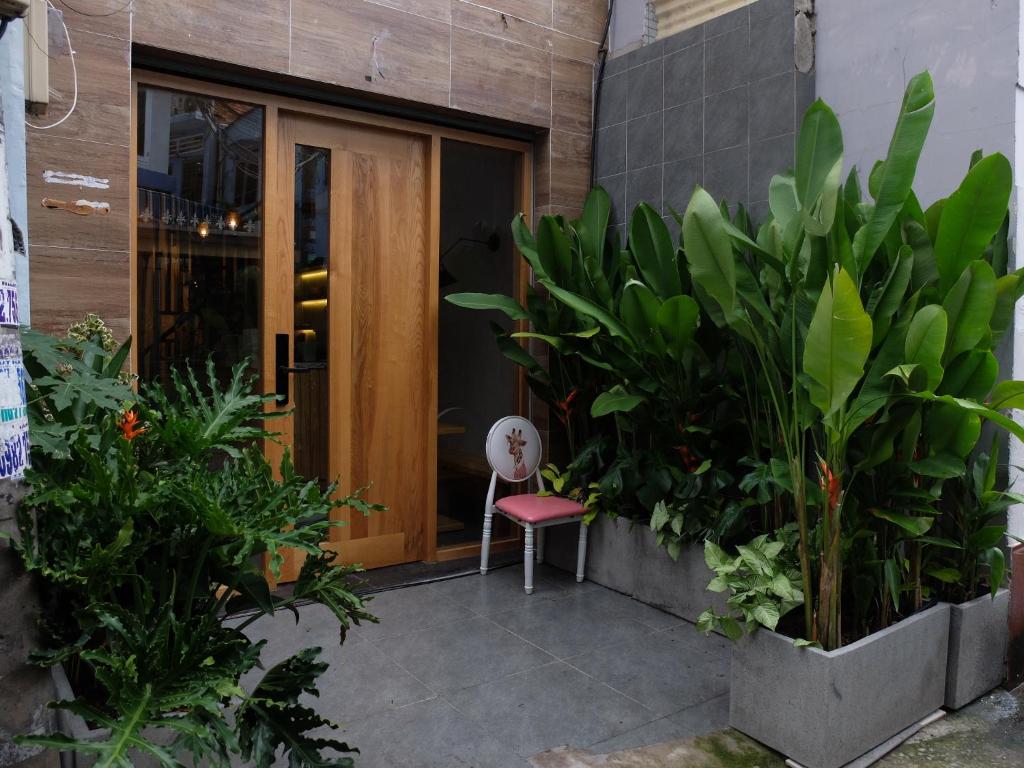 胡志明市HALF Coffee N Dorm的坐在一扇门前的椅子,有植物