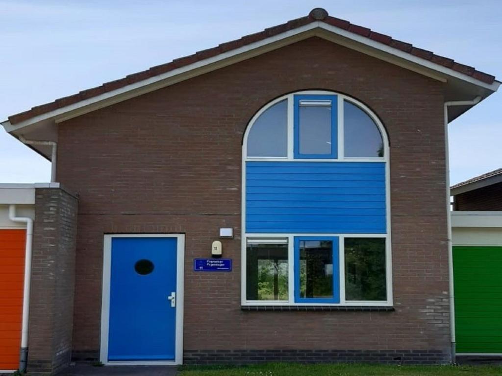 弗拉讷克Semi detached house in Franeker with a shared pool的一座带蓝色门和窗户的房子