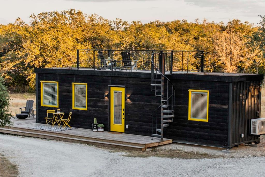 弗雷德里克斯堡New The Yellow Beacon-Luxury Shipping Container的一间黑色的小房子,设有黄色的门和甲板