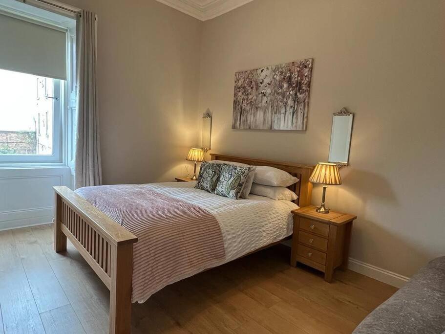 格拉斯哥Luxury Victorian spacious flat的一间卧室配有一张带两盏灯的床和一扇窗户。