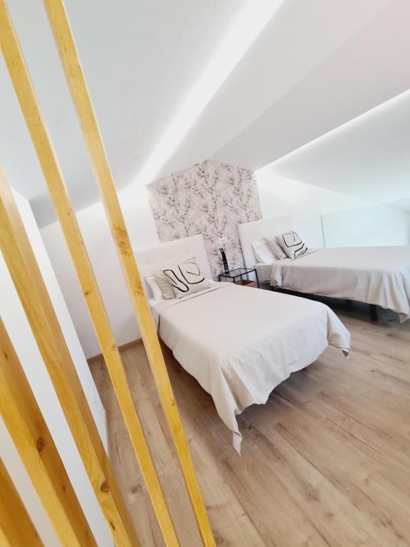 阿吉拉海滩INFINITY VIEW的配有白色墙壁和木地板的客房内的两张床