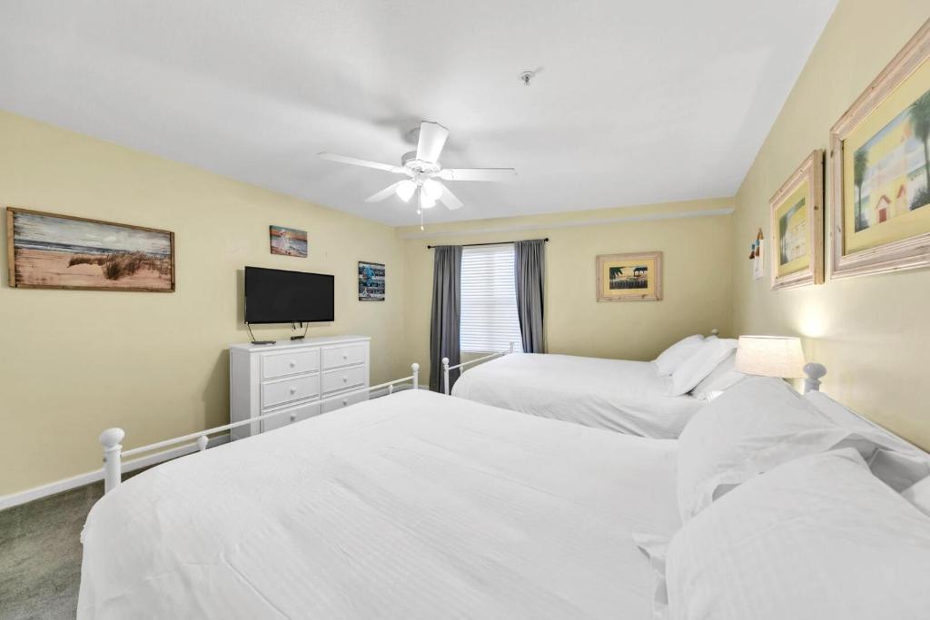 德斯坦Amalfi Coast 113B - Steps from the Beach 2BD 2BA的一间卧室，配有两张床和一台平板电视
