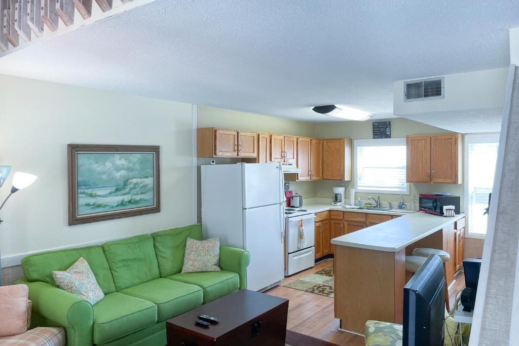 海洋岛海滩Starboard #16C的一间带绿色沙发的客厅和一间厨房