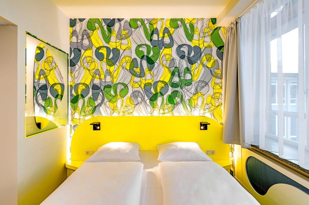 多特蒙德prizeotel Dortmund-City的一间卧室设有两张床和彩色的墙壁