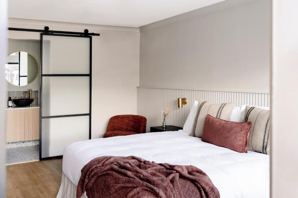 卡伦德拉Motel Caloundra的卧室配有白色的床和红色椅子