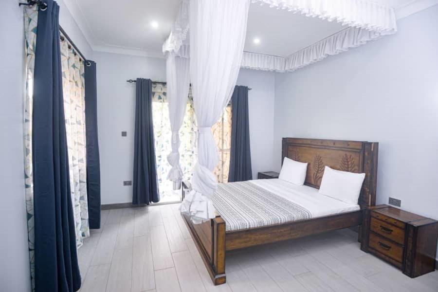 坎帕拉PearlCrest townhomes的一间卧室配有一张带白色床单和窗帘的床